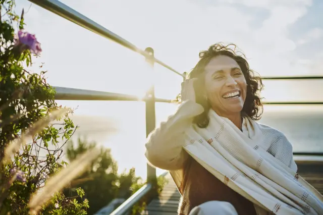 woman laughing sitting on deck with back facing the shore.