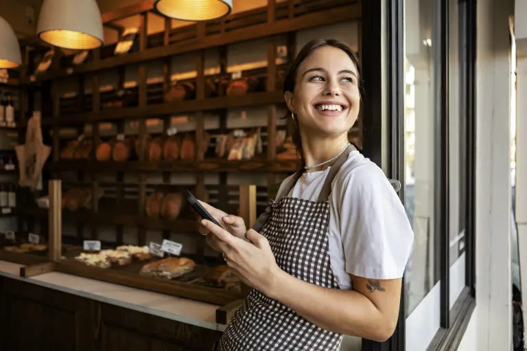 woman working at bakery standing in the doorway smiling.